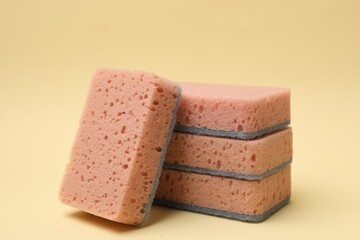 Pink kitchen sponges on beige background, closeup