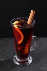 Tasty mulled wine in glass mug on black table, closeup