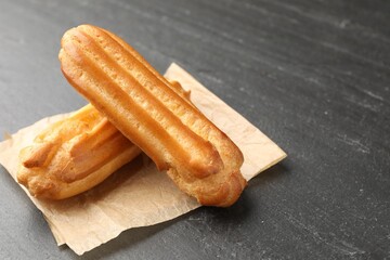 Tasty eclairs on black table, closeup. Space for text