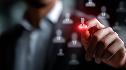 Hand selecting one illuminated red user icon from gray icons defocused background personnel choice visualization candidate identification display hiring selection symbolism