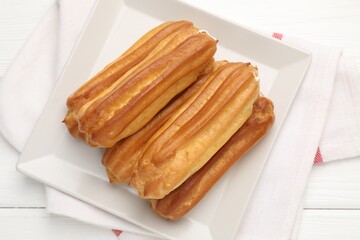 Tasty eclairs on white wooden table, top view