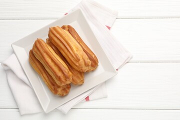Tasty eclairs on white wooden table, top view. Space for text