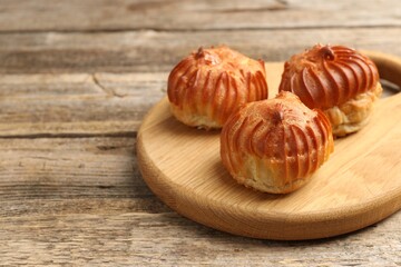 Tasty profiteroles on wooden table, closeup. Space for text