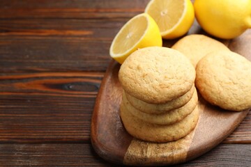 Tasty lemon cookies and fruits on wooden table, closeup. Space for text