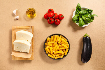 A variety of fresh ingredients for cooking are arranged on a kitchen counter, including tomatoes, cheese, basil, garlic, olive oil, and pasta. These elements inspire a flavorful meal.