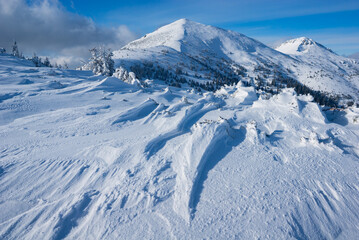 View of a snow-covered mountain range under a clear blue sky, the crisp white snow contrasting with the deep blue shadows, in Babky, Western Tatras, Jamnik, Zilinsky kraj, Slovakia.
