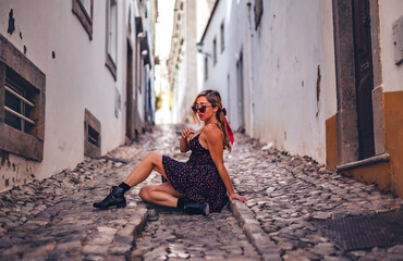 Woman resting on cobblestone street in the historic old town of Tavira, Algarve