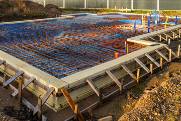 Underfloor heating system with pipes installed over rebar grid before concrete slab pouring