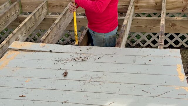 Workman prying old boards off of supporting joists