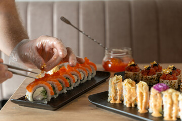 A chef decorates fresh, high-end sushi rolls with edible gold flakes