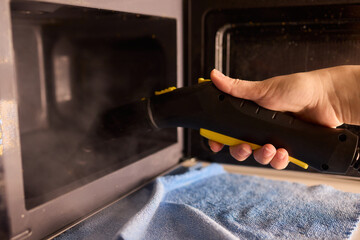 Cleaning microwave safely, Handheld steamer removes grime from microwave cavity efficiently, Ecofriendly steam cleaning method focuses on hygiene and appliance preservation
