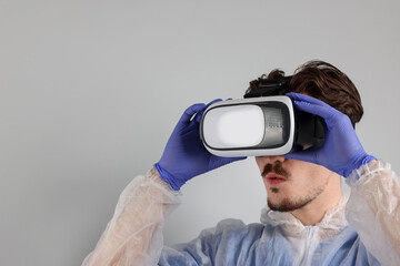 Modern technology. Doctor using virtual reality headset on grey background. Space for text