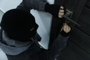 Thief in mask breaking into house indoors, above view