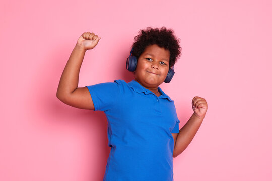 Cute little boy in headphones on pink background