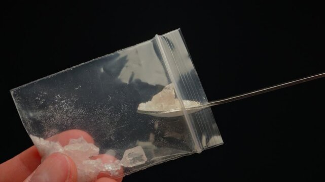 Drug dealer showing Fentanyl Crystal meth or Crack Cocaine for sale and distribution. Drug trafficking and addiction crises. Crystals use in glass tube or stems and primarily smoking or as powder.