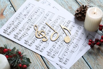 Golden music notes, sheets and Christmas decor on wooden table, closeup