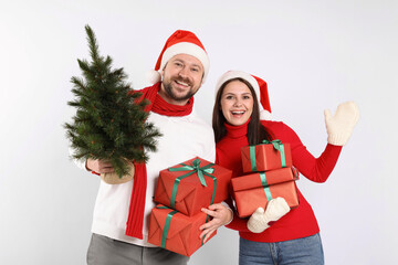 Happy couple with Christmas tree and gifts on white background