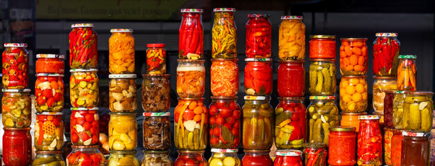 Colorful jars of pickled vegetables line a market stall with vibrant preserves