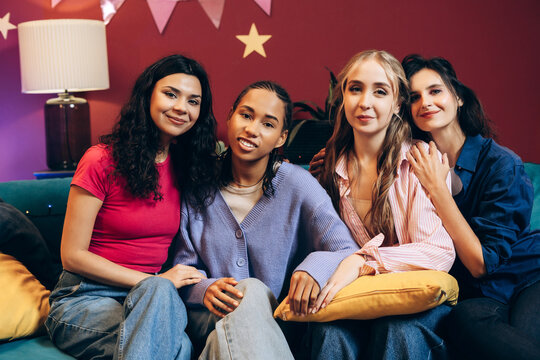 Diverse young women celebrating friendship and togetherness on sofa