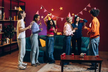 Group of multinational young friends celebrating birthday party at home