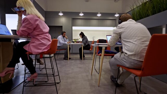 Focused business people diligently work on their tasks, both individually and collaboratively, within a vibrant and modern office space. Productivity and teamwork define the corporate atmosphere.