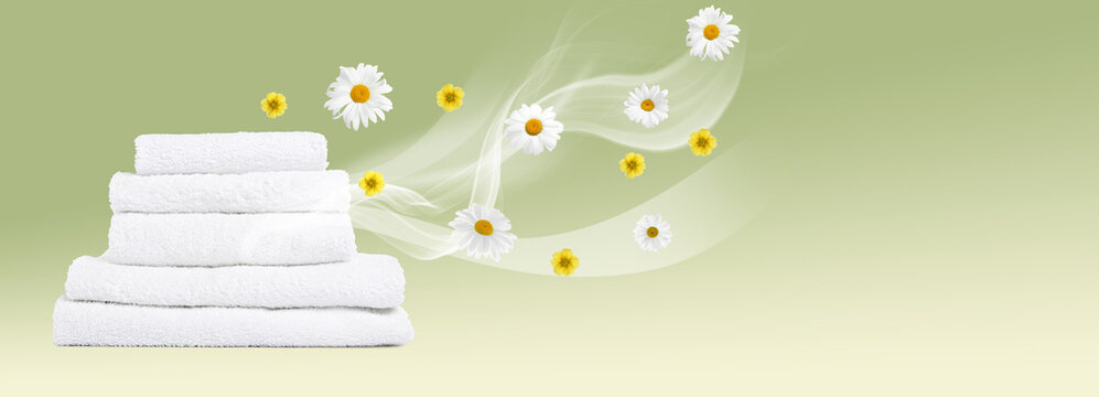 Fresh, pleasantly scented towels on light green background. Flows of aroma and flowers from laundry. Using of fabric softener or detergent