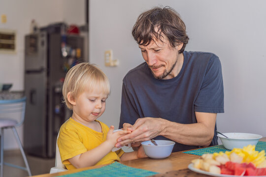 A father having breakfast at the table with his young son in a bright home kitchen, sharing a warm morning moment. Family bonding, parenting, everyday routine and healthy lifestyle concept