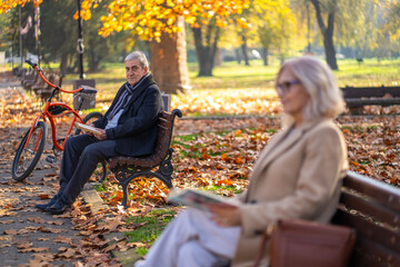 Senior couple enjoying a relaxing autumn day in the park with a bicycle