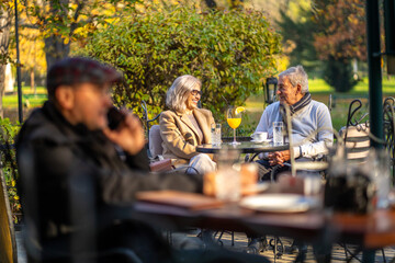 Senior couple enjoying drinks and conversation at an outdoor cafe on a sunny day