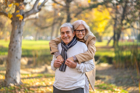Happy senior couple embracing outdoors in a park during the autumn season