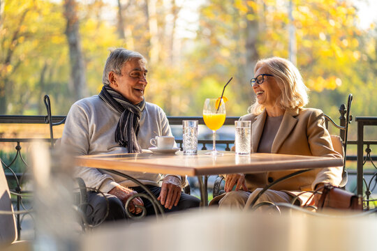 Happy senior couple enjoying drinks and conversation at an outdoor cafe