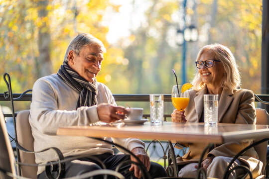 Happy senior couple enjoying drinks and conversation at an outdoor cafe