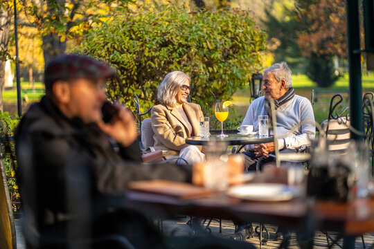 Senior couple enjoying drinks and conversation at an outdoor cafe on a sunny day