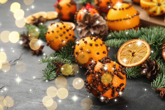 Fresh tangerines decorated with cloves (Pomander balls) and fir tree branches on table, bokeh lights