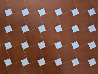 Square brown terracotta or porcelain stoneware floor or wall tile texture with diagonal pattern and white inserts. Tiled surface, classic tiles, Victorian or Mediterranean style, rustic, traditional. 