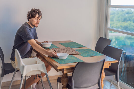 A man preparing breakfast at a kitchen table in a bright modern home, captured in a candid moment with natural light. Domestic life, morning routine, healthy living and slow living lifestyle concept