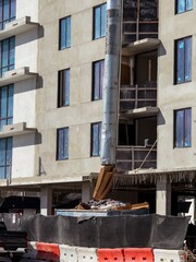 Suspended sections of metal garbage chute on a facade of building under construction 
