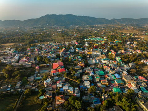 Aerial view of the town nestled amid rolling hills, where rooftops create a vibrant tapestry under the expansive sky, Bir, Himachal Pradesh, India.