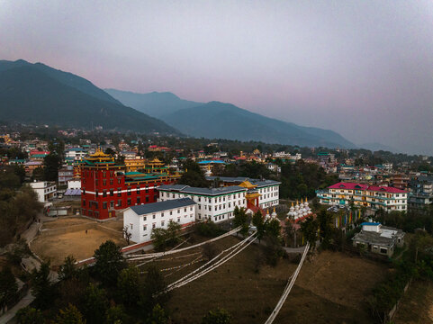 Aerial view of the vibrant monasteries and stupas nestled amidst the mountainous landscape, a fusion of red, white, and gold against the backdrop of the Himalayas, Bir, Himachal Pradesh, India.