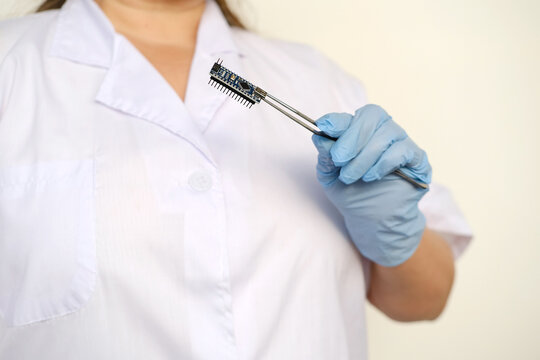scientist, electronic engineer holds electronic chip, bug, microcontrollers in hand, Electronics components, circuit building, electrical engineering, neural implants, Neurotechnology Advancements