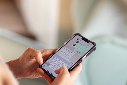 Close-up of hands using smartphone for messaging with colorful chat interface displayed