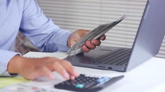 Financial planning, Home finances, budget, savings and spends concept. Counting cash dollars in front of a laptop and plotting them into several sections