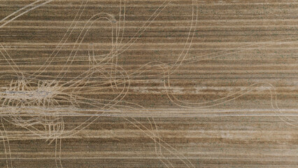 Abstract top-down aerial view of a harvested field showing complex patterns of tire tracks overlaid on the linear stubble