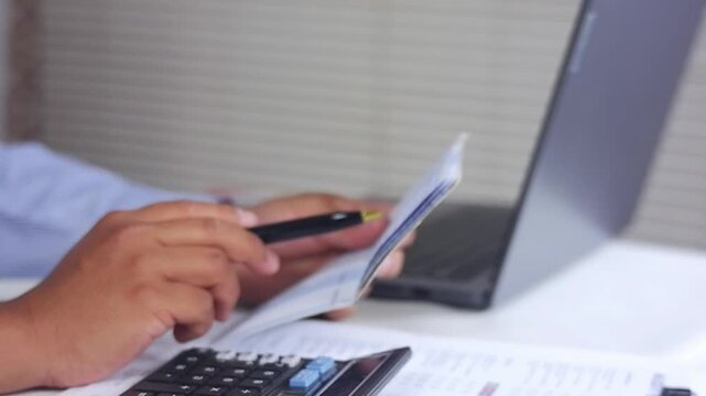 Men's hands holding savings books and preparing budgets. Looking at savings books in front of computers.calculating household budgets and expenses.Insurance or mortgages.Household financial management