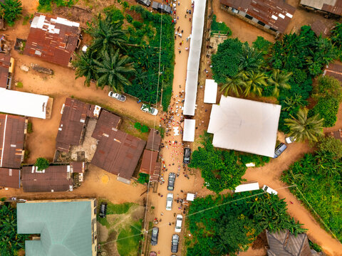 Aerial view of a bustling street with dense vegetation and varied rooftops, showcasing the vibrant life of Orlu Local Government Area, Owerri, Imo State, Nigeria.