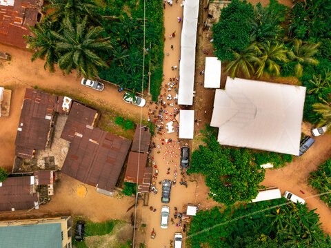 Aerial view of a bustling street scene, with crowds gathered amidst buildings and lush greenery under an overcast sky, Owerri, Imo State, Nigeria.