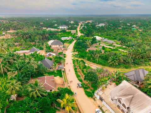Aerial view of a winding road cutting through lush green trees, interspersed with buildings, creating a vibrant contrast under the expansive sky, Owerri, Imo State, Nigeria.