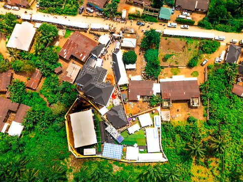 Aerial view of rooftops with contrasting dark and light tones amidst lush greenery, and roads with vehicles, Owerri, Imo State, Nigeria.