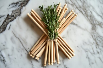 Wooden rods with fresh rosemary on marble surface