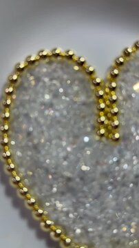 A heart made of polished golden hematite beads with shimmering triangular glass beads inside. Sparkling, jewelry-grade materials perfect for craft, design, and holiday themes